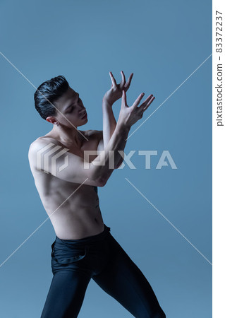 Portrait of young man, flexible male ballet dancer dancing isolated on old navy studio background. Art, motion, inspiration concept. Portrait of young man, flexible male ballet dancer dancing isolated on old navy studio background. Art, motion, inspiration concept. 83372237