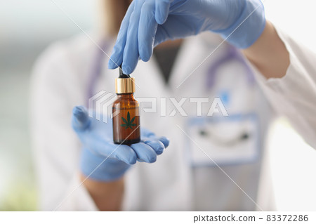 Scientist chemist in protective gloves holding hemp oil in jar closeup 83372286