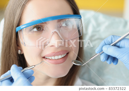 Dentist doctor holding medical instruments in front of smiling patient in clinic Dentist doctor holding medical instruments in front of smiling patient in clinic 83372322