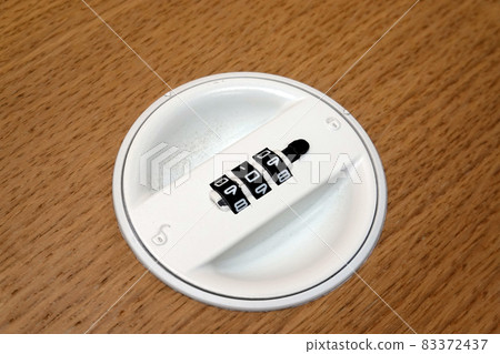 A white combination dial on a file cabinet. a wood background A white combination dial on a file cabinet. a wood background 83372437