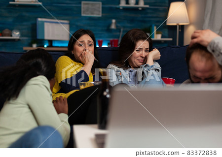 Terrified scared group of people watching horror scary movie on laptop Terrified scared group of people watching horror scary movie on laptop 83372838