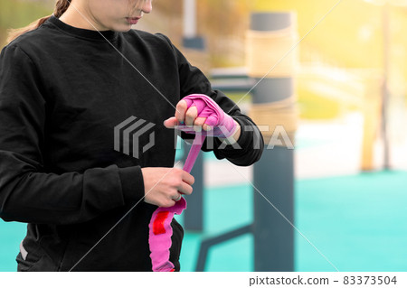 girl wrapping a wrist wrap around her hand before outdoor martial arts training girl wrapping a wrist wrap around her hand before outdoor martial arts training 83373504