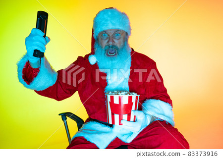 Portrait of senior man, surprised Santa Claus sitting and watching movie at cinema, indoors. Happy New Year 2022, Christmas concept Portrait of senior man, surprised Santa Claus sitting and watching movie at cinema, indoors. Happy New Year 2022, Christmas concept 83373916
