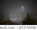 Eerie sky scraper hospital lights shine through very thick fog. 83374498
