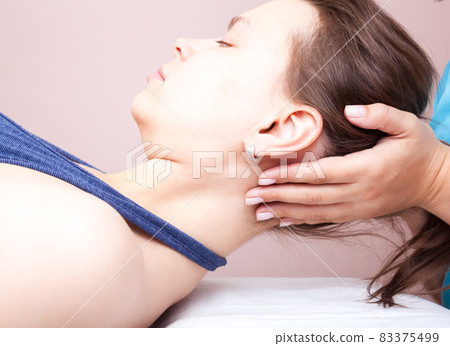 Woman receiving osteopathic treatment of her neck 83375499