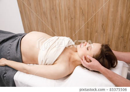 Pregnant woman receiving osteopathic treatment of her head Pregnant woman receiving osteopathic treatment of her head 83375506