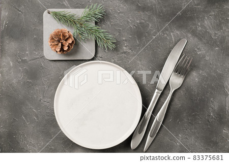 empty plate with silverware and christmas tree branch and cone on grey table. copy space. table setting template for new year or christmas menu. restaurant menu mock up. top view empty plate with silverware and christmas tree branch and cone on grey table. copy space. table setting template for new year or christmas menu. restaurant menu mock up. top view 83375681