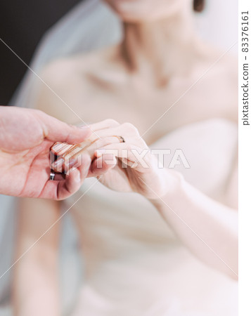 Bride in wedding dress holding groom's hand Bride in wedding dress holding groom's hand 83376161