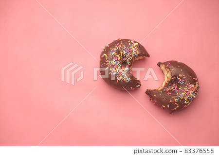 top view of half eaten chocolate donuts on pink  83376558