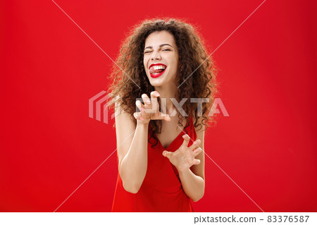 Roar gonna eat you sweetie. Sensual and seductive playful european woman with curly hairstyle forplaying in bedroom with lover in red evening dress making animal paws sticking out tongue and winking Roar gonna eat you sweetie. Sensual and seductive playful european woman with curly hairstyle forplaying in bedroom with lover in red evening dress making animal paws sticking out tongue and winking 83376587