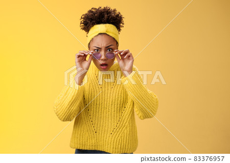 Shocked speechless impressed african-american stylish female coworker drop jaw look amazed take-off sunglasses widen eyes cannot believe confused standing yellow background questioned stare camera 83376957
