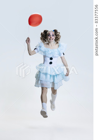 Full-length portrait of young girl wearing Halloween dress, costume of clown walking isolated over grey background Full-length portrait of young girl wearing Halloween dress, costume of clown walking isolated over grey background 83377556
