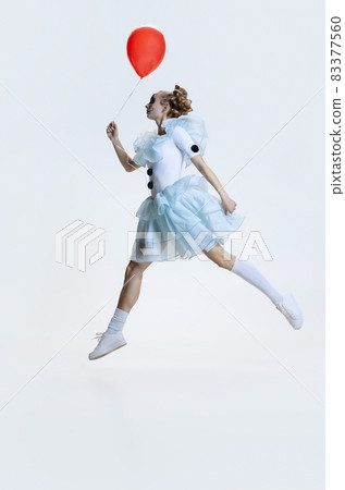 Full-length portrait of young girl wearing Halloween dress, costume of clown jumping isolated over grey background 83377560