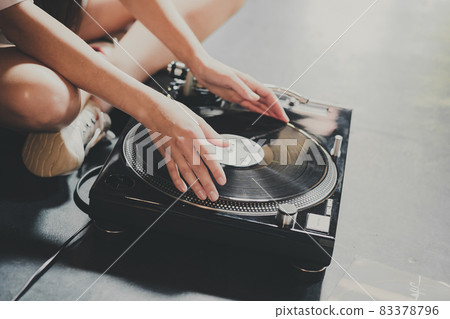 A young woman sits on the floor and explores vinyl records, puts them on a retro player. A young woman sits on the floor and explores vinyl records, puts them on a retro player. 83378796