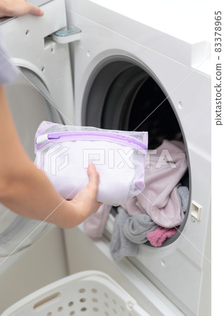 Hands of a housewife who puts it in the laundry net and does fashionable clothes washing 83378965