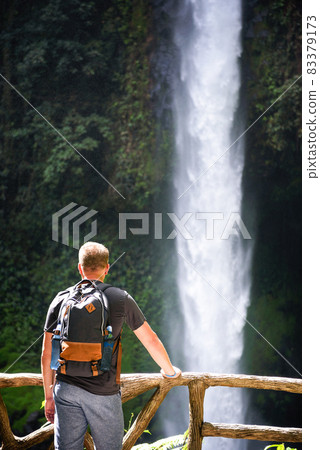 Tourist looking at the La Fortuna Waterfall in Costa Rica Tourist looking at the La Fortuna Waterfall in Costa Rica 83379173
