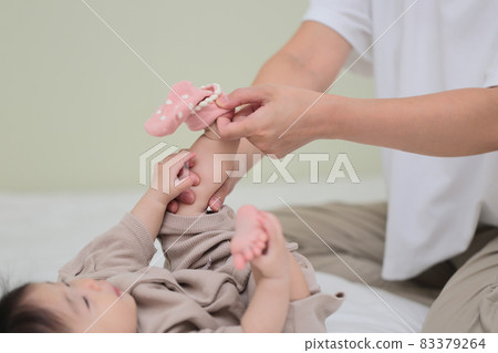 Mom putting socks on a baby in the second half of life 83379264