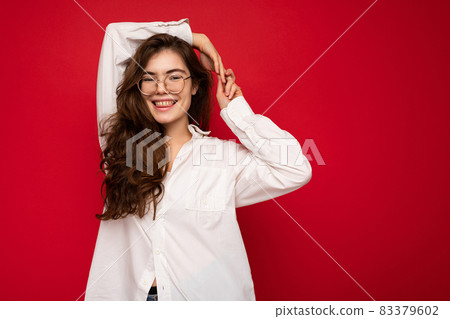 Portrait of beautiful positive cheerful cute smiling young brunette woman in casual white shirt and 83379602