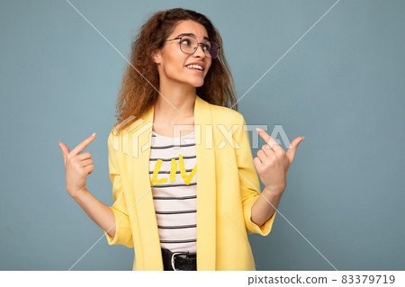 Photo of young positive beautiful brunette curly woman with sincere emotions wearing casual yellow 83379719