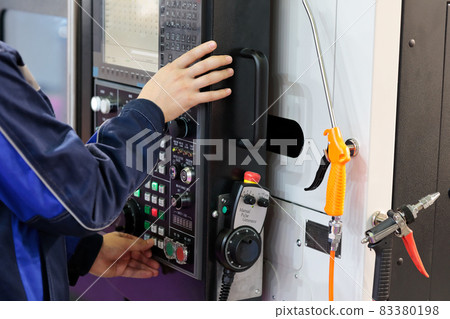 worker adjusts the parameters of the CNC machine worker adjusts the parameters of the CNC machine 83380198