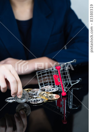 Woman holding some pieces of golden Bitcoin token in shopping cart Woman holding some pieces of golden Bitcoin token in shopping cart 83380319
