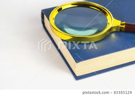Magnifying glass and blue closed book in hardcover. Minimalist c 83383129