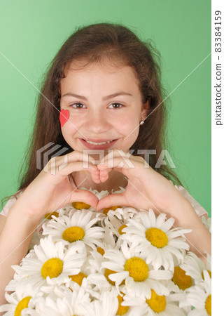 Portrait of a young girl with a bouquet of chamomiles. 83384159