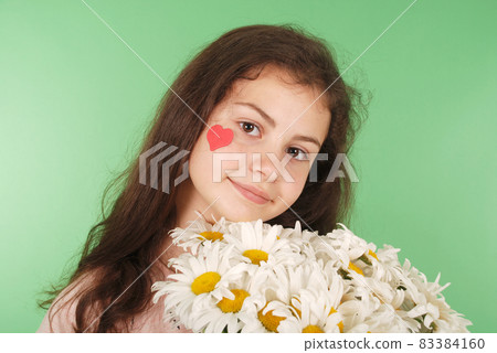 Portrait of a young girl with a bouquet of chamomiles. 83384160
