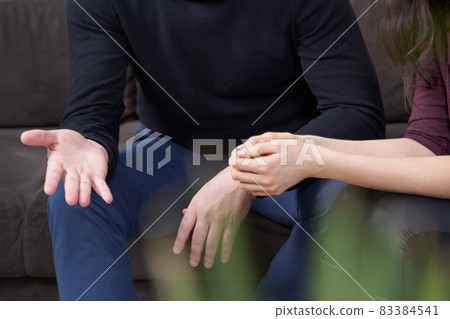Cropped view of man and woman talking while sitting on a couch Cropped view of man and woman talking while sitting on a couch 83384541