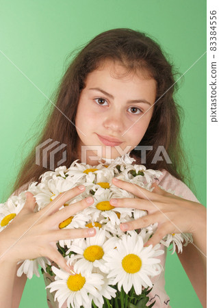 Portrait of a young girl with a bouquet of chamomiles. 83384556