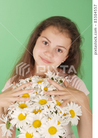 Portrait of a young girl with a bouquet of chamomiles. Portrait of a young girl with a bouquet of chamomiles. 83384557