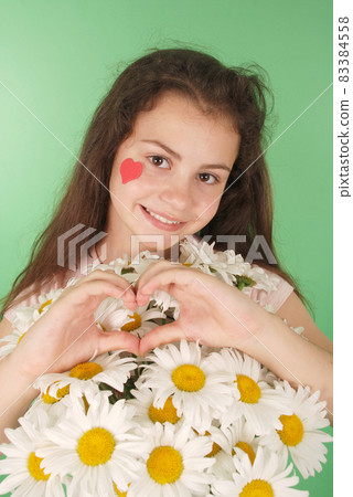 Portrait of a young girl with a bouquet of chamomiles. 83384558
