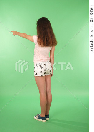 Side view young girl with raised hand looking at wall. Side view young girl with raised hand looking at wall. 83384563