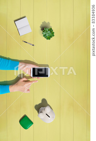 Person using smartphone with piggy bank Person using smartphone with piggy bank 83384936