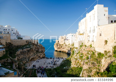 View of the beach lama monachile cala porto and white buildings on grottos and cliffs in the town of Polignano a mare 83384996