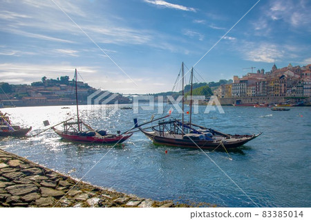 Portugal, city landscape Porto, a group of yellow wooden boats with wine port barrels on Douro river 83385014