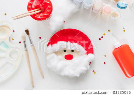 The child glues the parts Santa made from paper plate. Handmade. Project of children's creativity, handicrafts, crafts for kids. Preparation for christmas. Decoration. The child glues the parts Santa made from paper plate. Handmade. Project of children's creativity, handicrafts, crafts for kids. Preparation for christmas. Decoration. 83385056