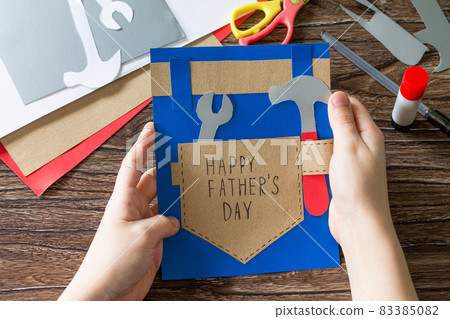 The child holds Greeting card with Happy fathers day. Children's art project craft for kids. Craft for children. 83385082