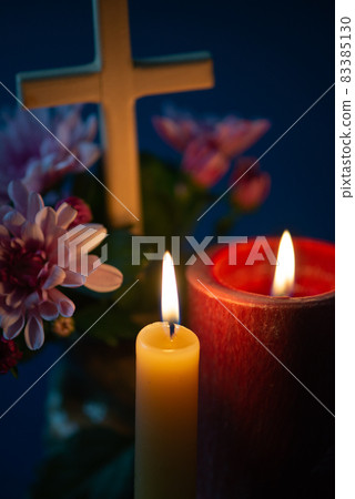 Composition of burning candle, flowers and wooden cross for all souls day. Also suitable for funeral, mourning, grief. 83385130