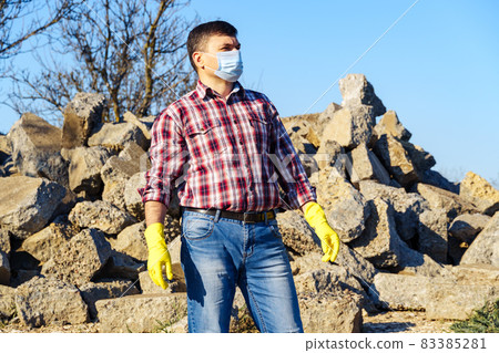 a man works with a pile of stones and broken pieces of concrete, carries construction debris a man works with a pile of stones and broken pieces of concrete, carries construction debris 83385281