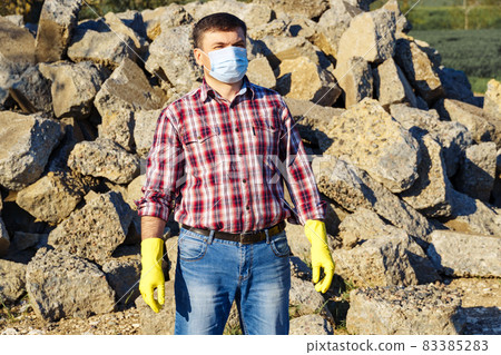 a man works with a pile of stones and broken pieces of concrete, carries construction debris a man works with a pile of stones and broken pieces of concrete, carries construction debris 83385283