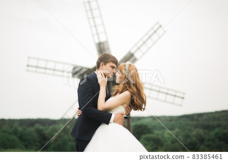 Emotional beautiful bride hugging newlywed groom at a field closeup 83385461
