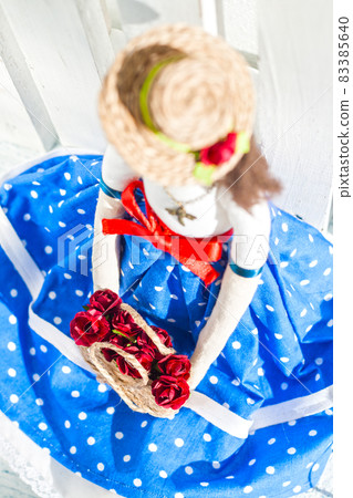 tilde doll in a blue skirt and a straw hat with a basket with flowers 83385640