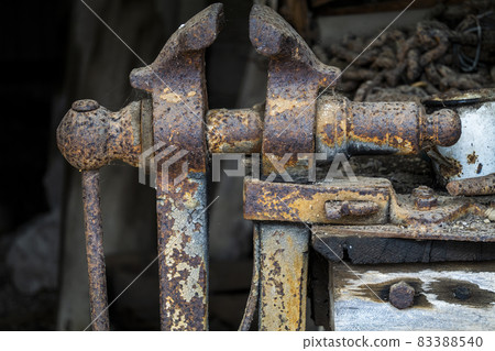 An old vintage clamp object pitted with rust left in a shed amongst other vintage artifacts An old vintage clamp object pitted with rust left in a shed amongst other vintage artifacts 83388540