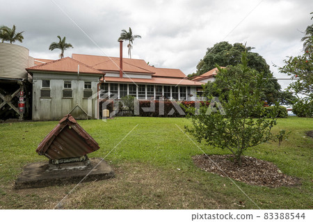 Back of an historical heritage listed homestead with a small old dog house in the garden under a cloudy sky 83388544