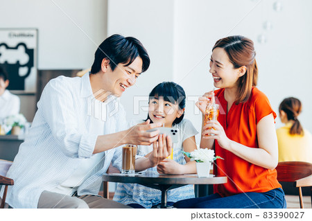 Young family looking at a smartphone at a cafe 83390027
