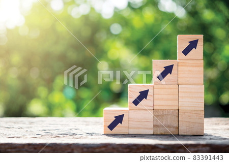 Wood block cubes stacking as step stair with arrow up on green nature background, Business concept growth success process. 83391443