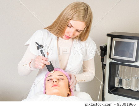 Young woman receiving treatment in cosmetology clinic. Cosmetology skin care. Aesthetic facial treatment Concept. Young woman receiving treatment in cosmetology clinic. Cosmetology skin care. Aesthetic facial treatment Concept. 83391960