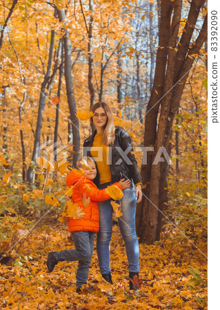 Mother hugging her child during walk in autumn park. Fall season and single parent concept. 83392090