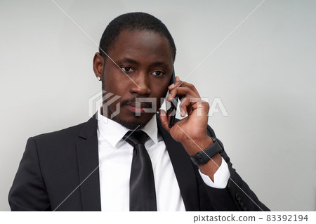 Closeup of angry young african man screaming while talking on smartphone over grey background 83392194